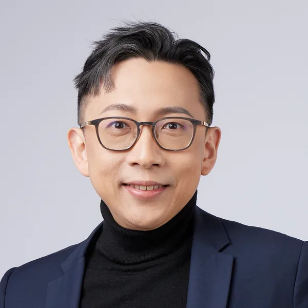 Ju-Chun Ko in a navy suit: smiling headshot
