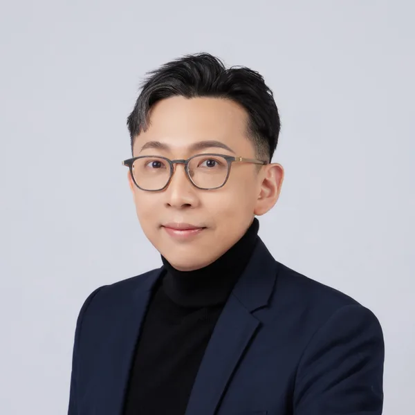 Ju-Chun Ko in a navy suit: angled headshot