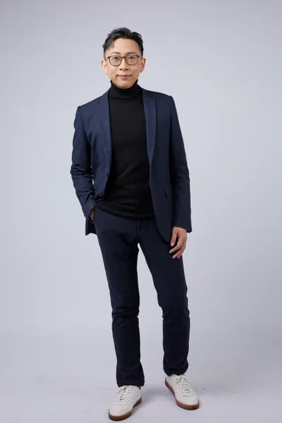 Ju-Chun Ko in a navy suit: standing portrait