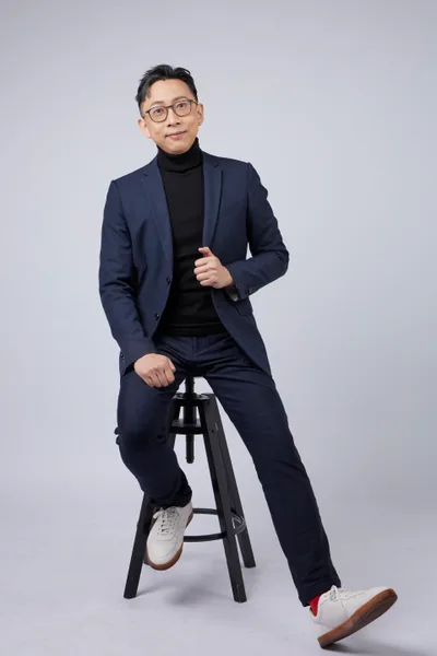 Ju-Chun Ko in a navy suit: seated full-length portrait