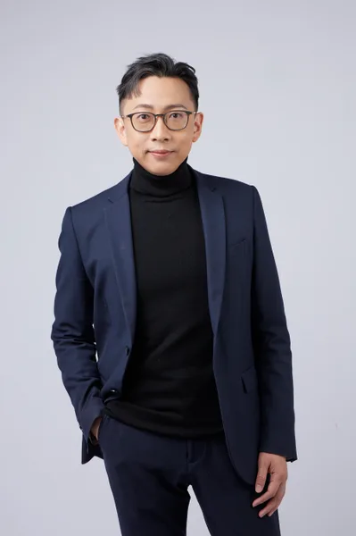 Ju-Chun Ko in a navy suit: standing half-length portrait